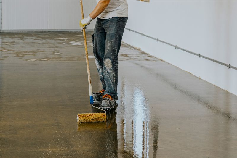 a man applying epoxy resin on a floor